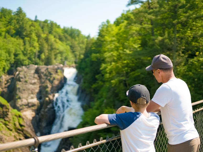 A man and his child observe the fall from the McNicoll Bridge in Sainte-Anne Canyon.