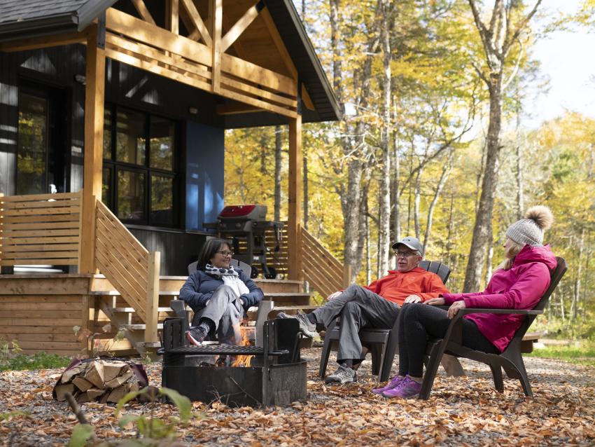 Friends around a fire outside, in front of a chalet in Jacques-Cartier National Park.