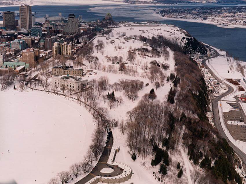 Commission des champs de bataille nationaux - Aerial view of the Plains of Abraham in winter with Old Québec and the St. Lawrence River in the background.