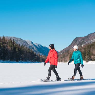 Two girls on snowshoes enjoy a sunny winter day in Jacques-Cartier National Park.