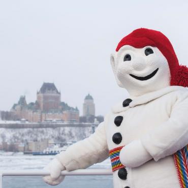 Bonhomme Carnaval is photographed on the exterior bridge of the Québec-Lévis Ferry, in winter.
