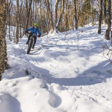 Un adepte de plein air pratique le vélo à roues surdimensionnées dans la forêt enneigée. 