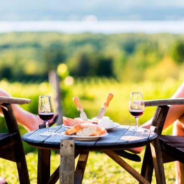 A couple discovers the regional products of the Ile d'Orléans while tasting wine and cheeses in a vineyard.