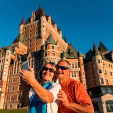 A couple takes a picture of themselves on the Dufferin terrace, in front of the Château Frontenac.