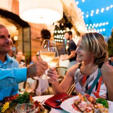 Un couple lève leurs verres et mange sur la terrasse d'un restaurant sur la rue Saint-Jean, en été. 