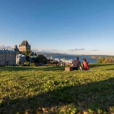 Pique-nique en couple près de la terrasse Pierre-Dugua-De Mons en admirant le Château Frontenac et le fleuve Saint-Laurent. 