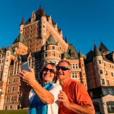 Un couple se prend en photo sur la terrasse Dufferin, devant le Château Frontenac.