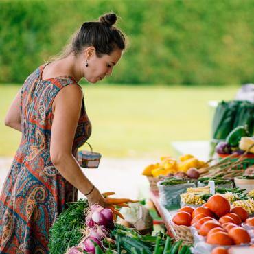 Un femme achète des fruits et des légumes frais dans un kiosque extérieur.