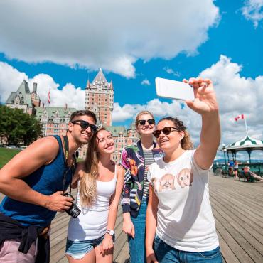 Quatre jeunes adultes se prennent en photo sur la terrasse Dufferin, à proximité du Château Frontenac.