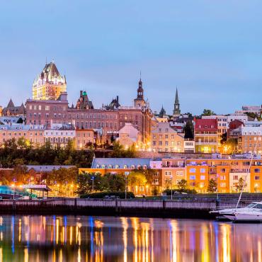 Voiliers au bassin Louise, dans le Vieux-Port de Québec, avec vue sur le Vieux-Québec illuminé.