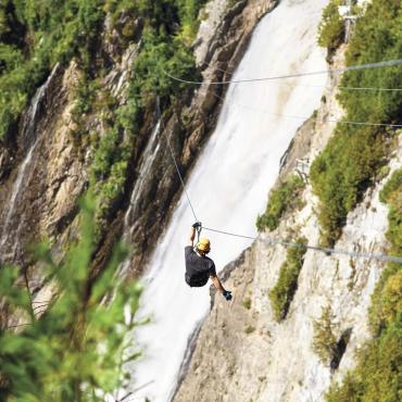 Un homme traverse l'anse de la chute en tyrolienne au Parc de la Chute Montmorency.